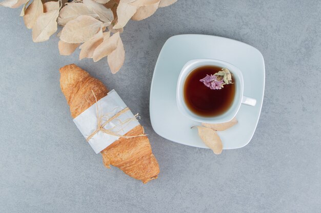 Té, croissants y hojas sobre el fondo de mármol. Foto de alta calidad