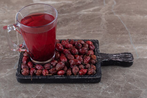 Té y fruta de rosa mosqueta en el tablero, en la superficie de mármol