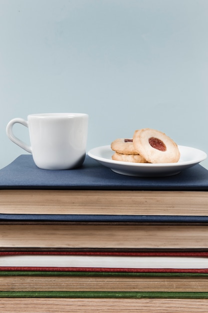 Foto gratuita té y galletas en la pila de libros