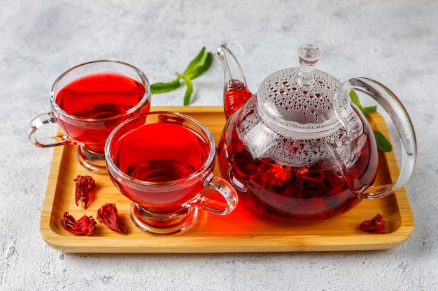 Té de hibisco caliente en una taza de vidrio y una tetera de vidrio.