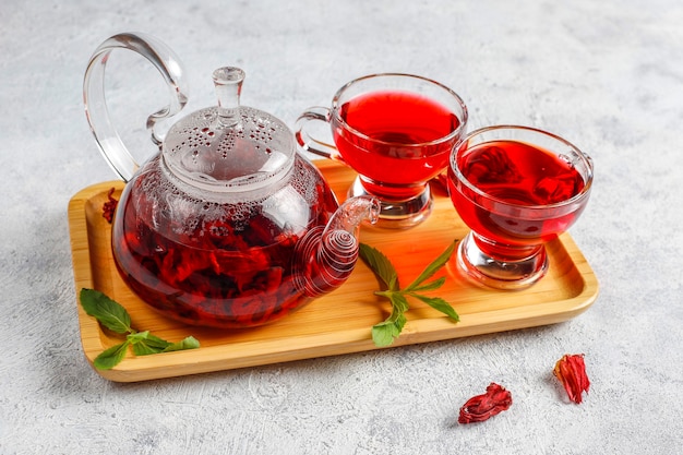 Té de hibisco caliente en una taza de vidrio y una tetera de vidrio.