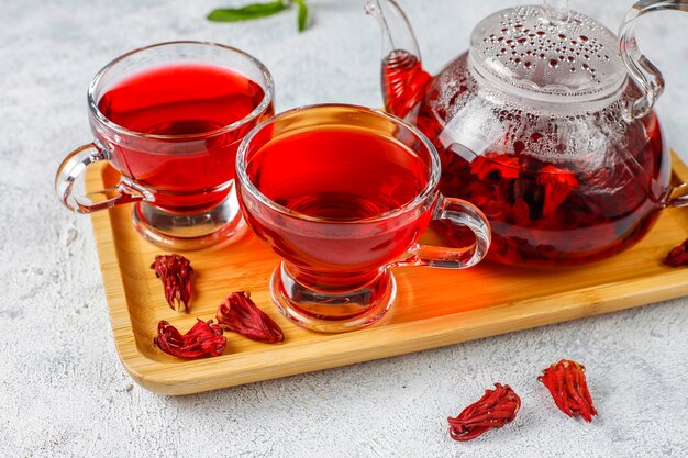 Té de hibisco caliente en una taza de vidrio y una tetera de vidrio.