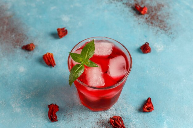 Té de hibisco frío con hielo y hojas de albahaca.