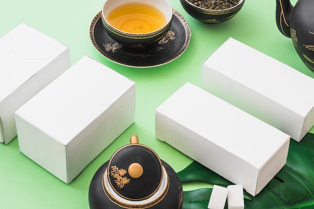 Foto gratuita té de hierbas con cuatro cajas blancas sobre fondo verde pálido