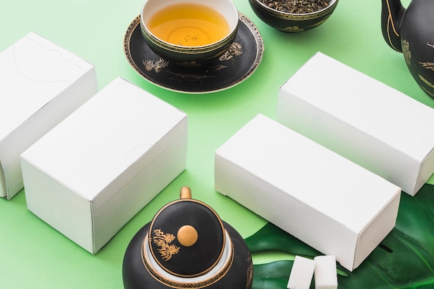 Té de hierbas con cuatro cajas blancas sobre fondo verde pálido