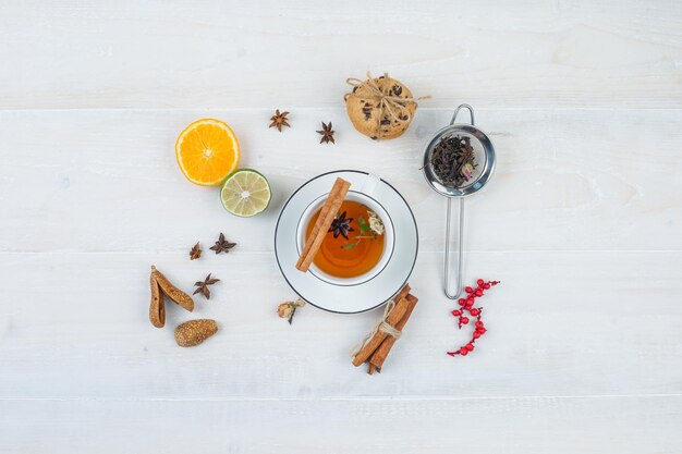 Té de hierbas y galletas con colador de té, hierbas, frutas cítricas