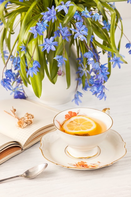 Té con limón y bouquet de prímulas azules sobre la mesa