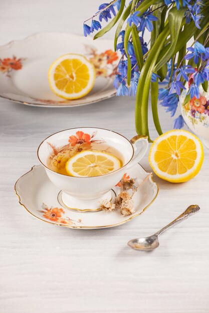 Té con limón y bouquet de prímulas azules sobre la mesa