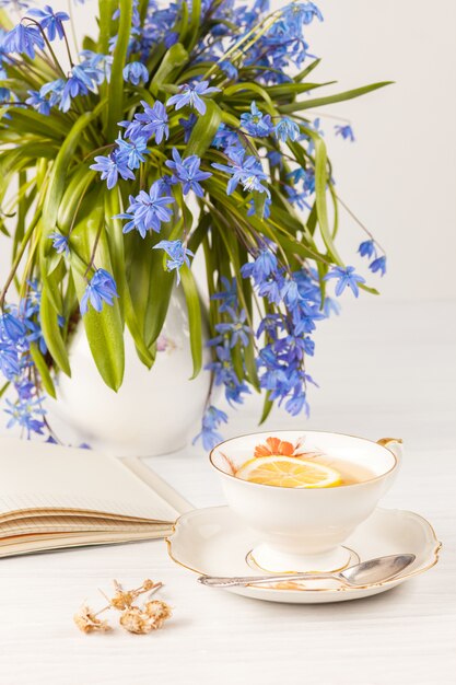 Té con limón y bouquet de prímulas azules sobre la mesa