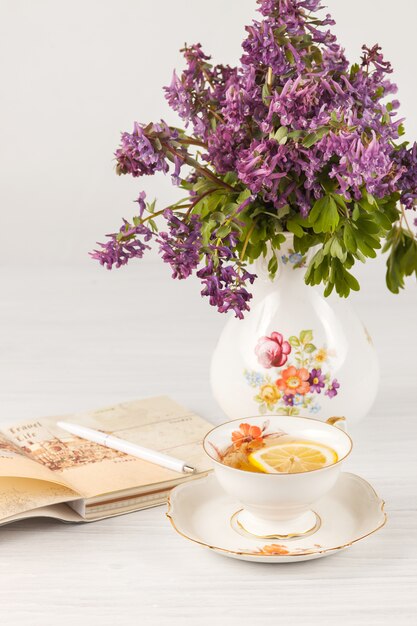 Té con limón y bouquet de prímulas lilas sobre la mesa