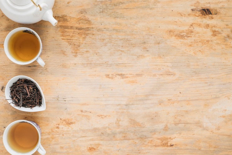 Foto gratuito té de limón con hojas secas de té y tetera en mesa de madera