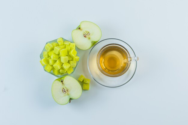 Té con manzana, terrones de azúcar en una taza sobre fondo blanco, plano laical.