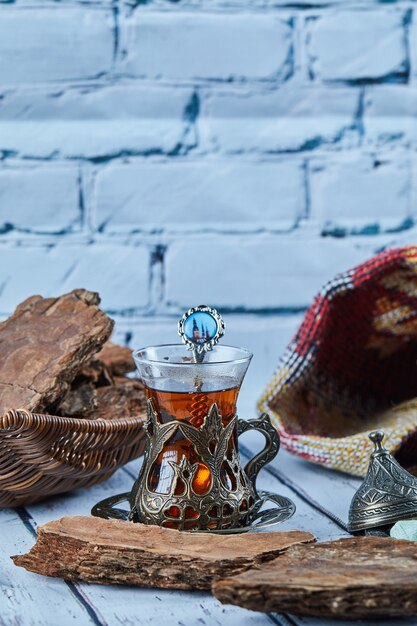 Té negro en una taza de cristal tradicional y galletas en la mesa de madera azul