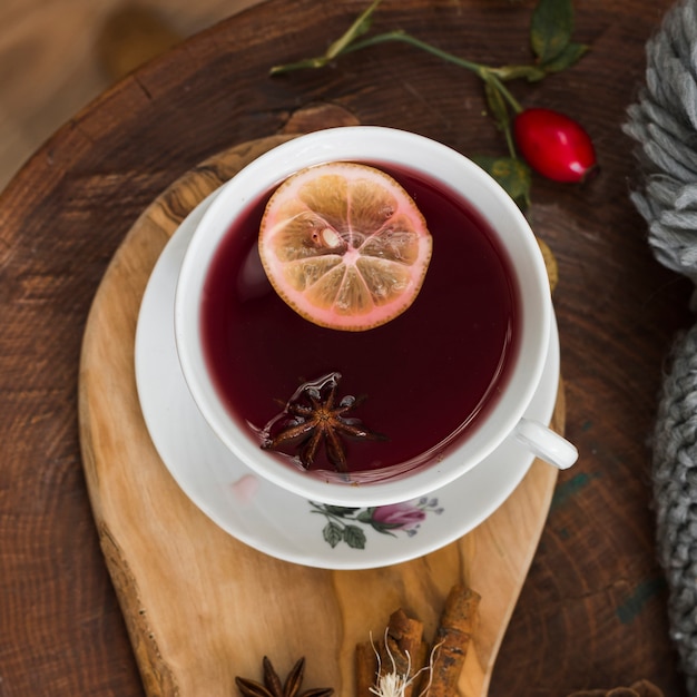 Té rojo con rodaja de limón en cojín de madera