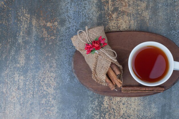 Té sabroso en taza blanca con canela en rama sobre tabla de madera.