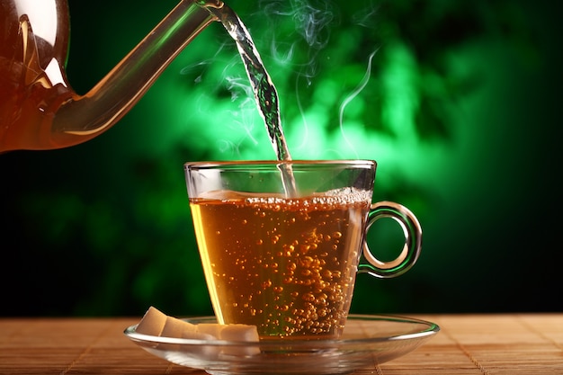 Té verde caliente en tetera de vidrio y taza