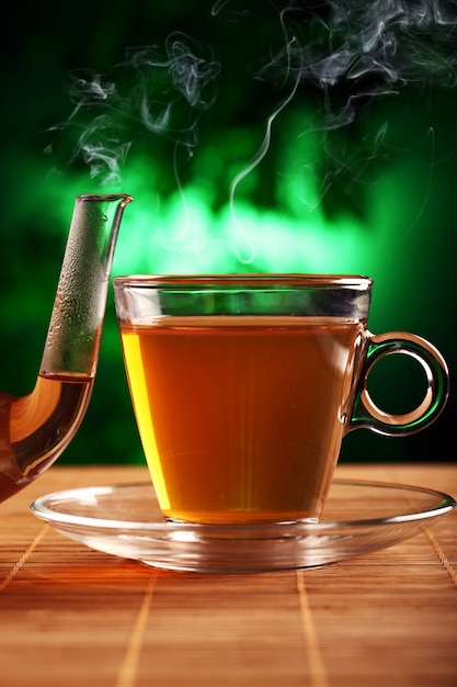 Té verde caliente en tetera de vidrio y taza