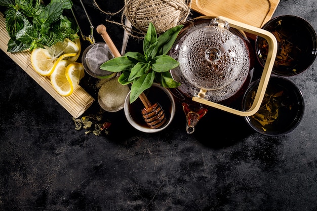 Té verde fresco sabroso en la ceremonia de la tetera de cristal en fondo oscuro arriba