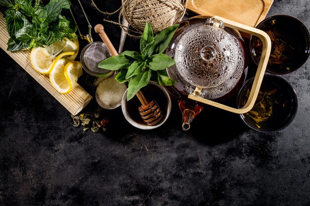 Té verde fresco sabroso en la ceremonia de la tetera de cristal en fondo oscuro arriba