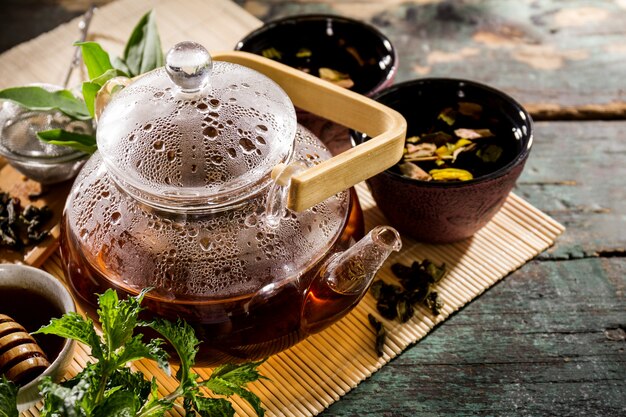 Té verde fresco sabroso en la ceremonia de la tetera de cristal en vieja tabla rústica