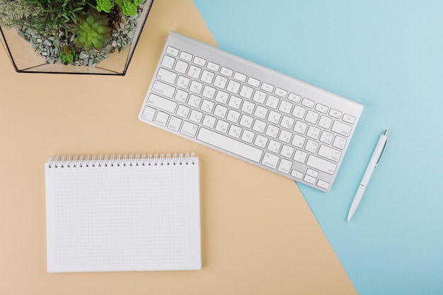 Teclado con cuaderno en blanco y planta