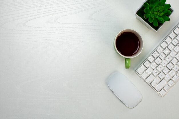 Teclado y mouse inalámbricos y taza de café sobre la mesa