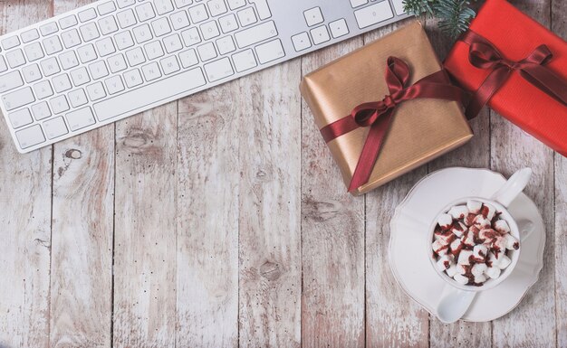 Teclado de ordenador, regalo de navidad y una taza con malvaviscos