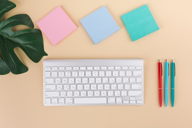 Foto gratuita teclado con pegatinas y bolígrafos sobre mesa.