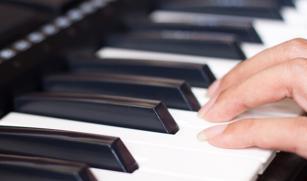 Teclado de piano con los dedos de la mujer