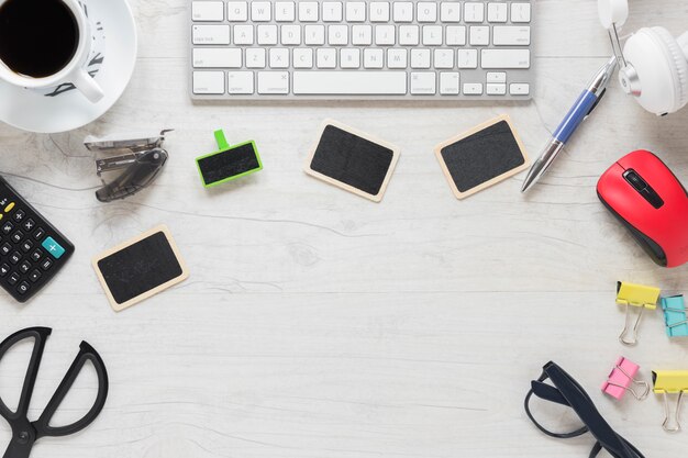 Teclado; tarjetas en blanco; Taza de café y suministros de oficina en el escritorio