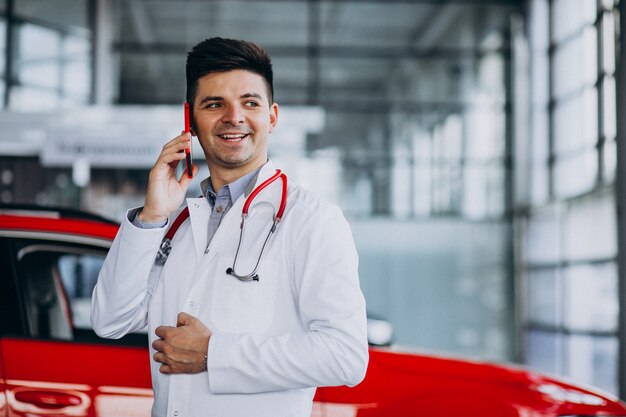 Técnico de automóviles con estetoscopio en una sala de exposición de automóviles hablando por teléfono