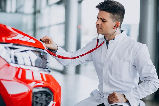 Técnico de automóviles con estetoscopio en una sala de exposición de automóviles