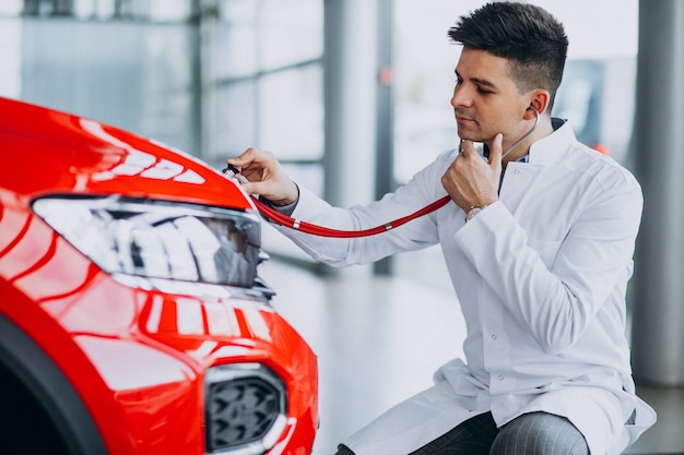 Técnico de automóviles con estetoscopio en una sala de exposición de automóviles