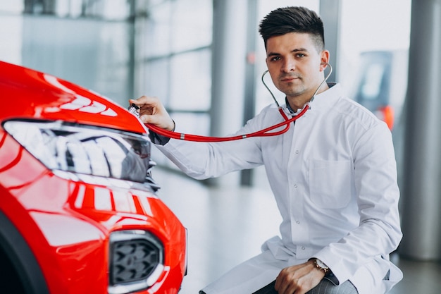 Técnico de automóviles con estetoscopio en una sala de exposición de automóviles