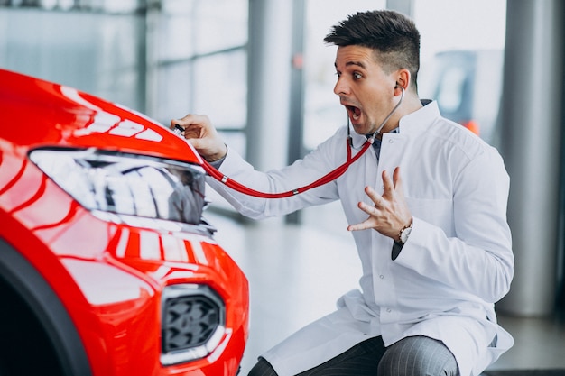 Técnico de automóviles con estetoscopio en una sala de exposición de automóviles