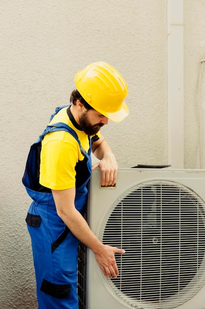 Técnico certificado preparando un nuevo acondicionador de aire exterior después de reemplazar la unidad vieja rota. Ingeniero capacitado contratado para instalar un nuevo condensador y asegurarse de que funcione a la máxima potencia