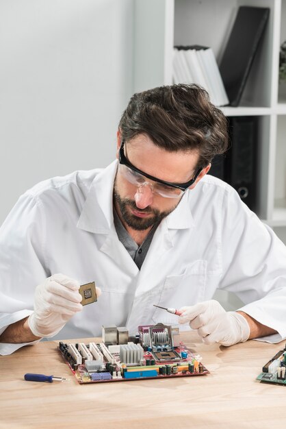 Técnico con chip de computadora con placa base en escritorio de madera