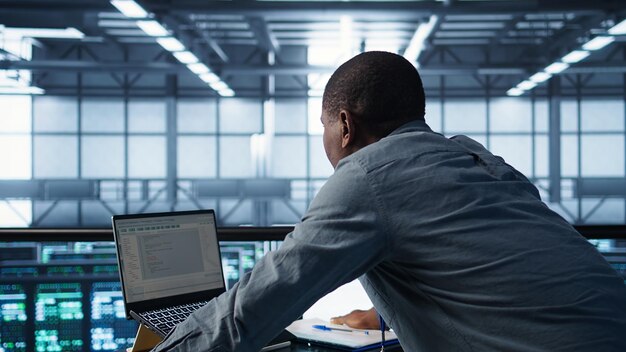 Técnico de codificación en portátil en el centro de datos que gestiona la virtualización del servidor