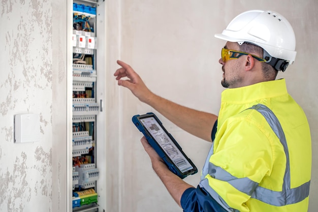 Técnico eléctrico que parece concentrado mientras trabaja en un cuadro de distribución con fusibles