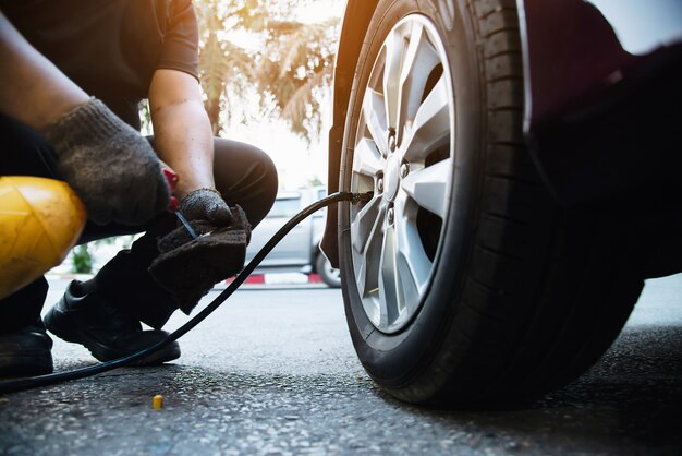 El técnico está inflando el neumático del automóvil - concepto de seguridad del transporte del servicio de mantenimiento del automóvil