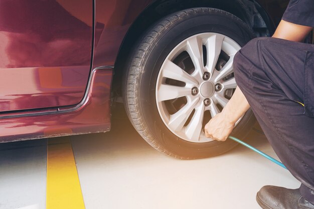 El técnico está inflando el neumático del automóvil - concepto de seguridad de transporte del servicio de mantenimiento del automóvil