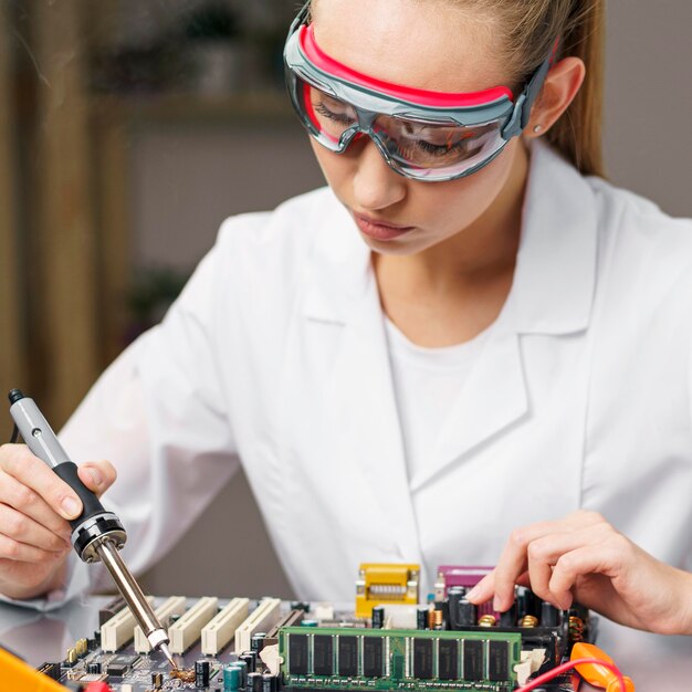 Técnico femenino con soldador y placa electrónica