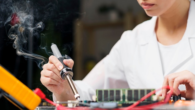 Foto gratuita técnico femenino con soldador y placa electrónica