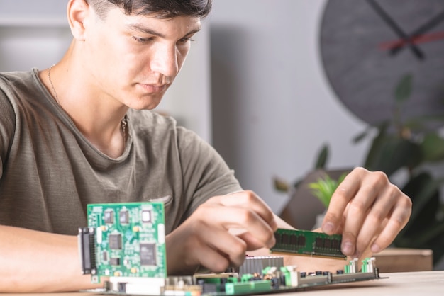 Técnico informático masculino que inserta la memoria RAM en la placa base de la computadora