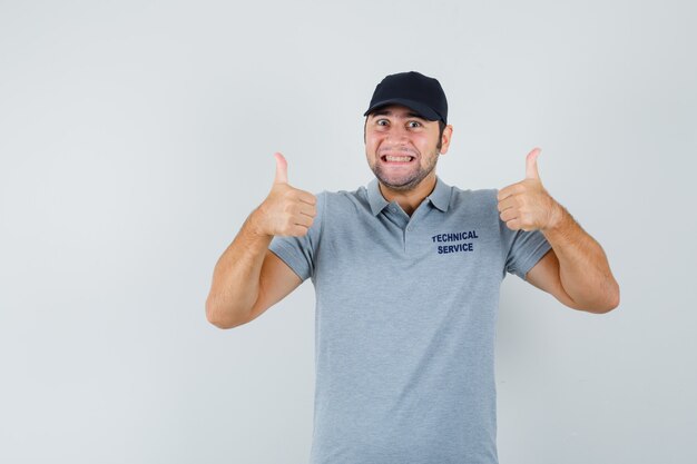 Técnico joven que muestra el pulgar doble hacia arriba en uniforme y parece alegre.