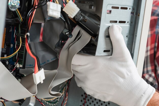 Técnico de la mano con guantes reparando computadora.