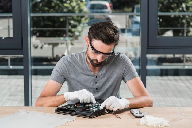 Técnico masculino joven que repara la computadora en taller