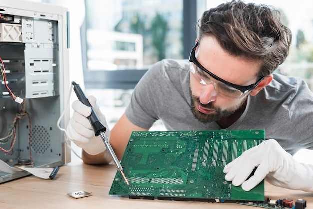Técnico masculino que repara la placa de circuito del ordenador