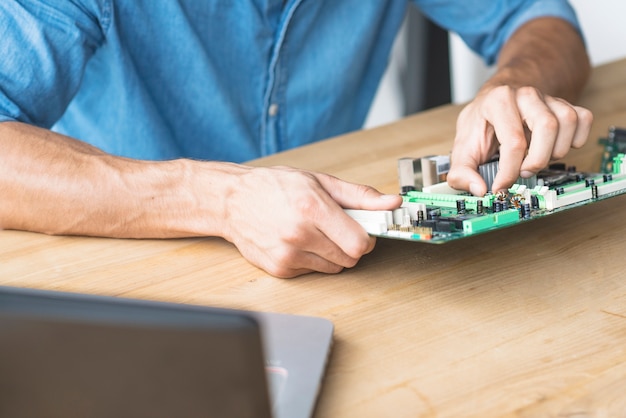 Técnico masculino que repara la placa madre en el banco de trabajo