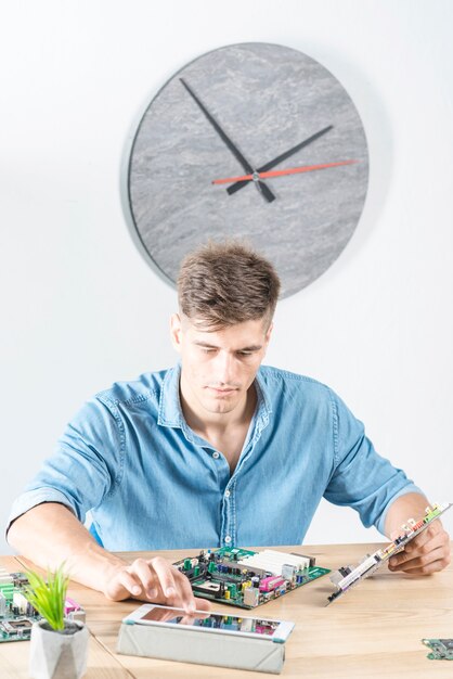 Técnico masculino que usa la tableta digital mientras que repara la placa madre